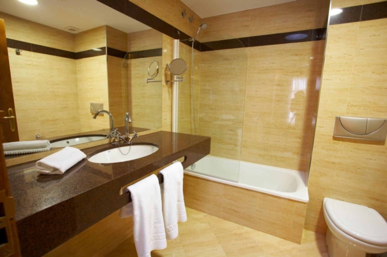 Un baño moderno con un lavamanos amplio, un espejo, una ducha y un inodoro.