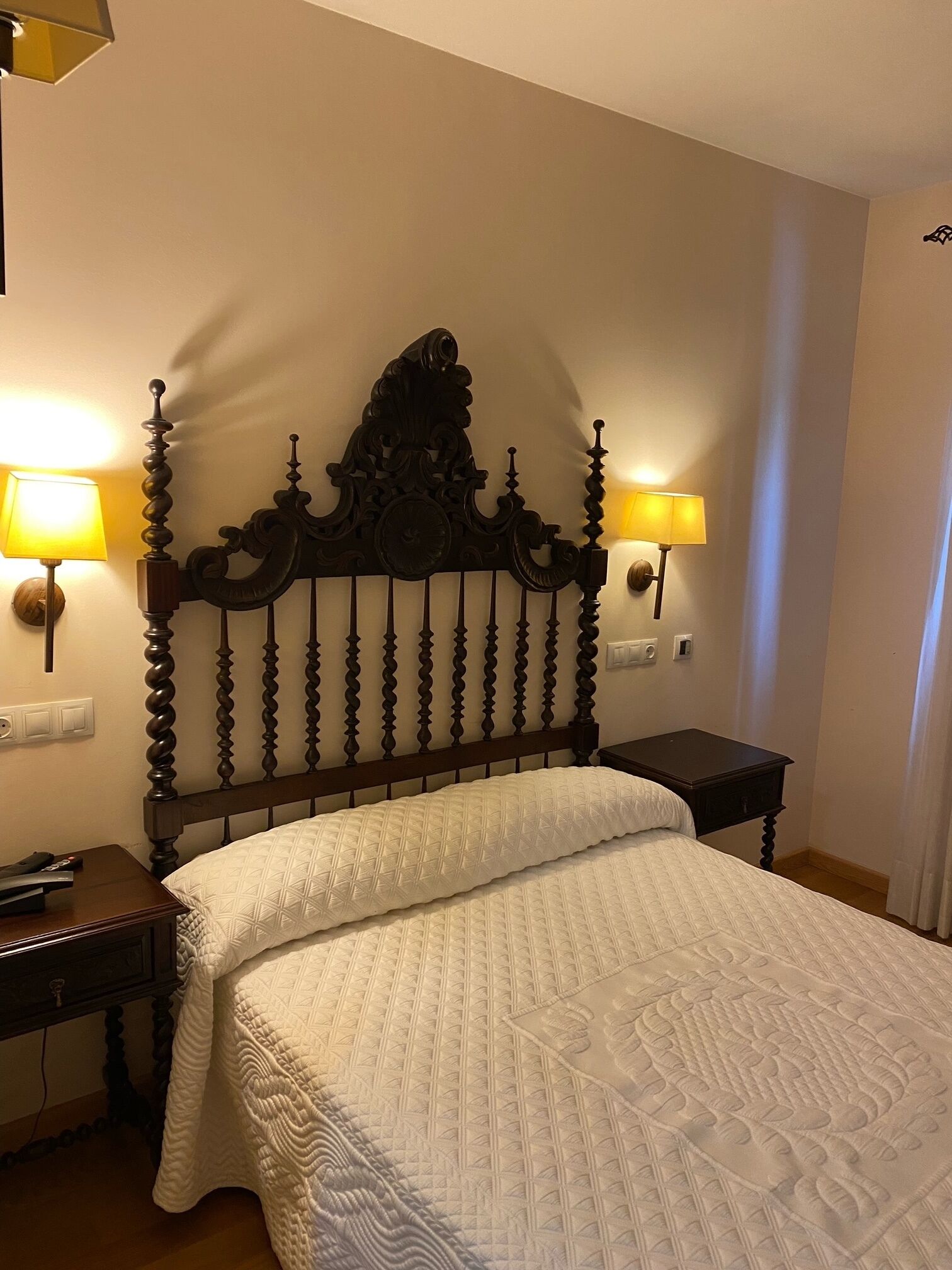 A hotel room with a large bed, two bedside tables, and a decorative headboard.