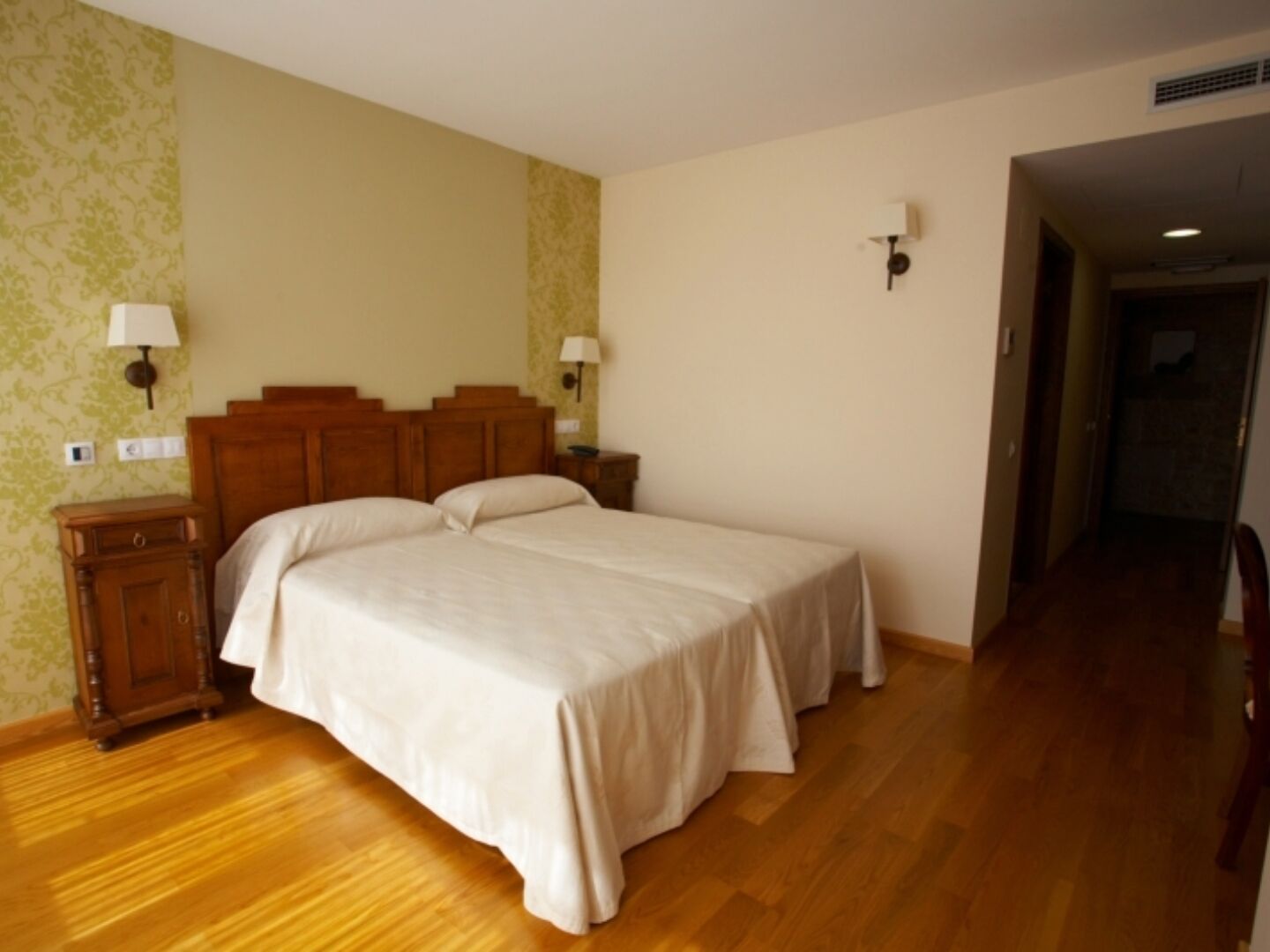 Une chambre à coucher avec un lit double, une tête de lit en bois, deux tables de chevet avec des lampes et un plancher en bois.