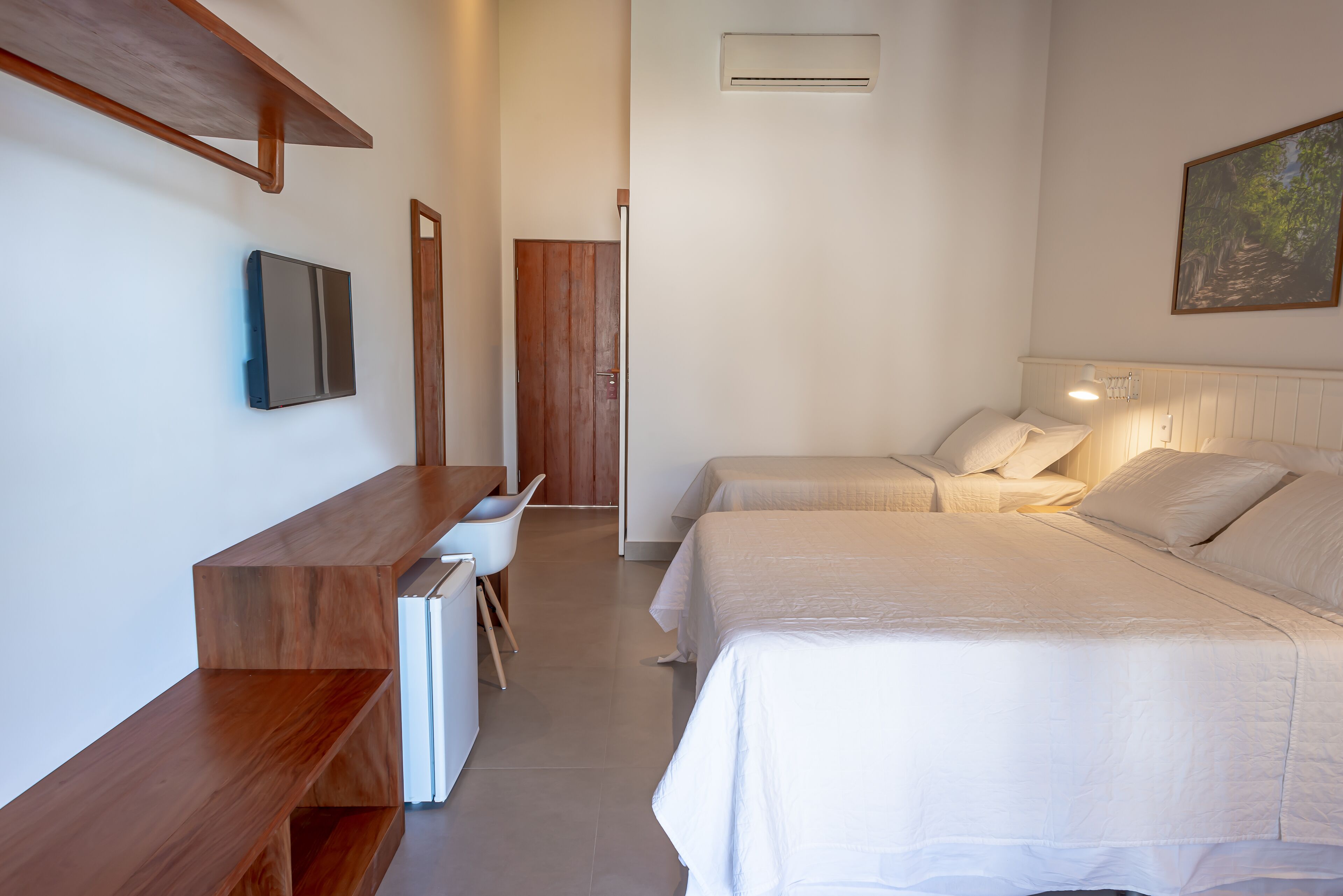 A hotel room with two beds, a desk, and a chair.