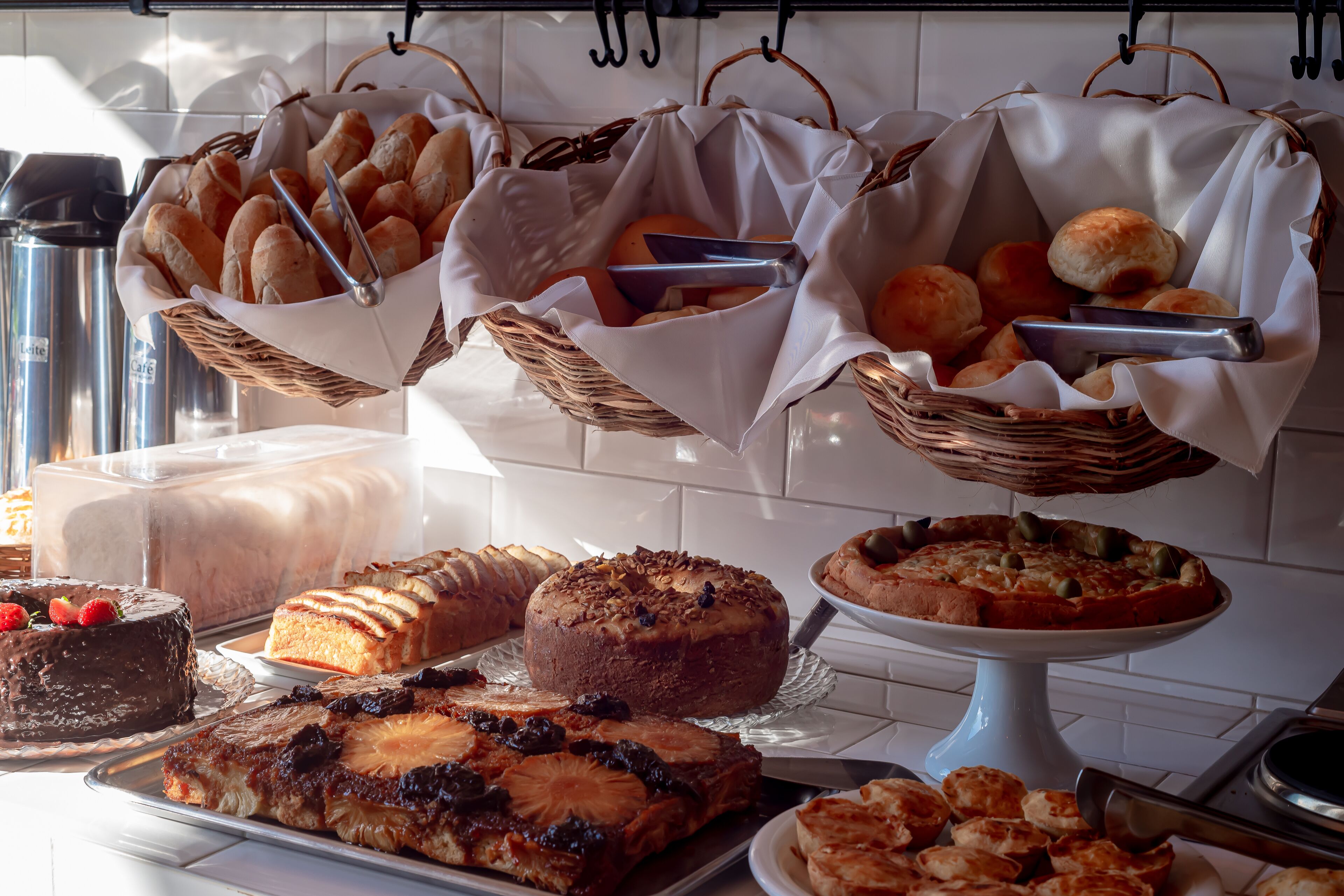 A buffet table with various baked goods, cakes, and a pie.