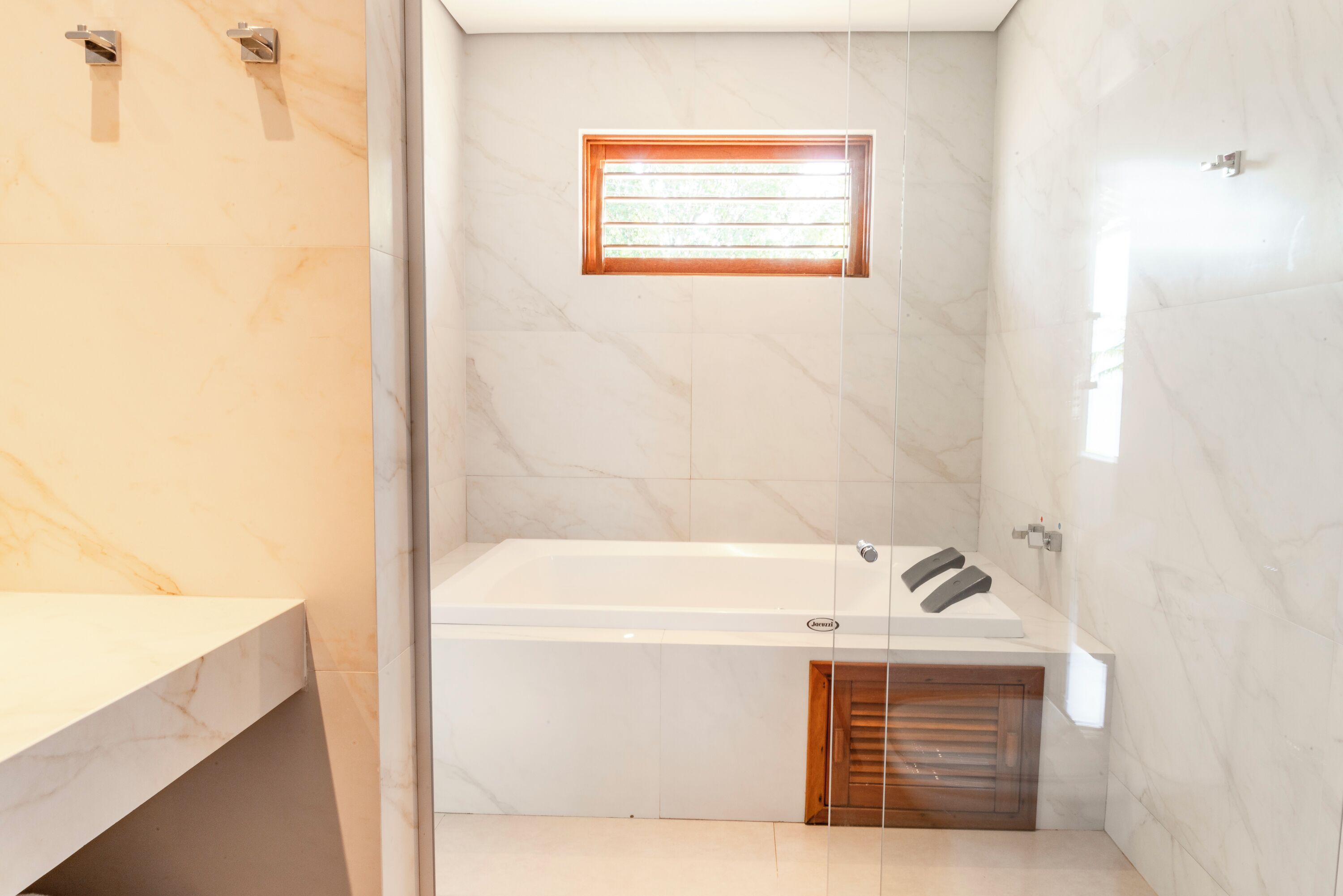 A modern bathroom with a bathtub, a small window, and a wooden door.
