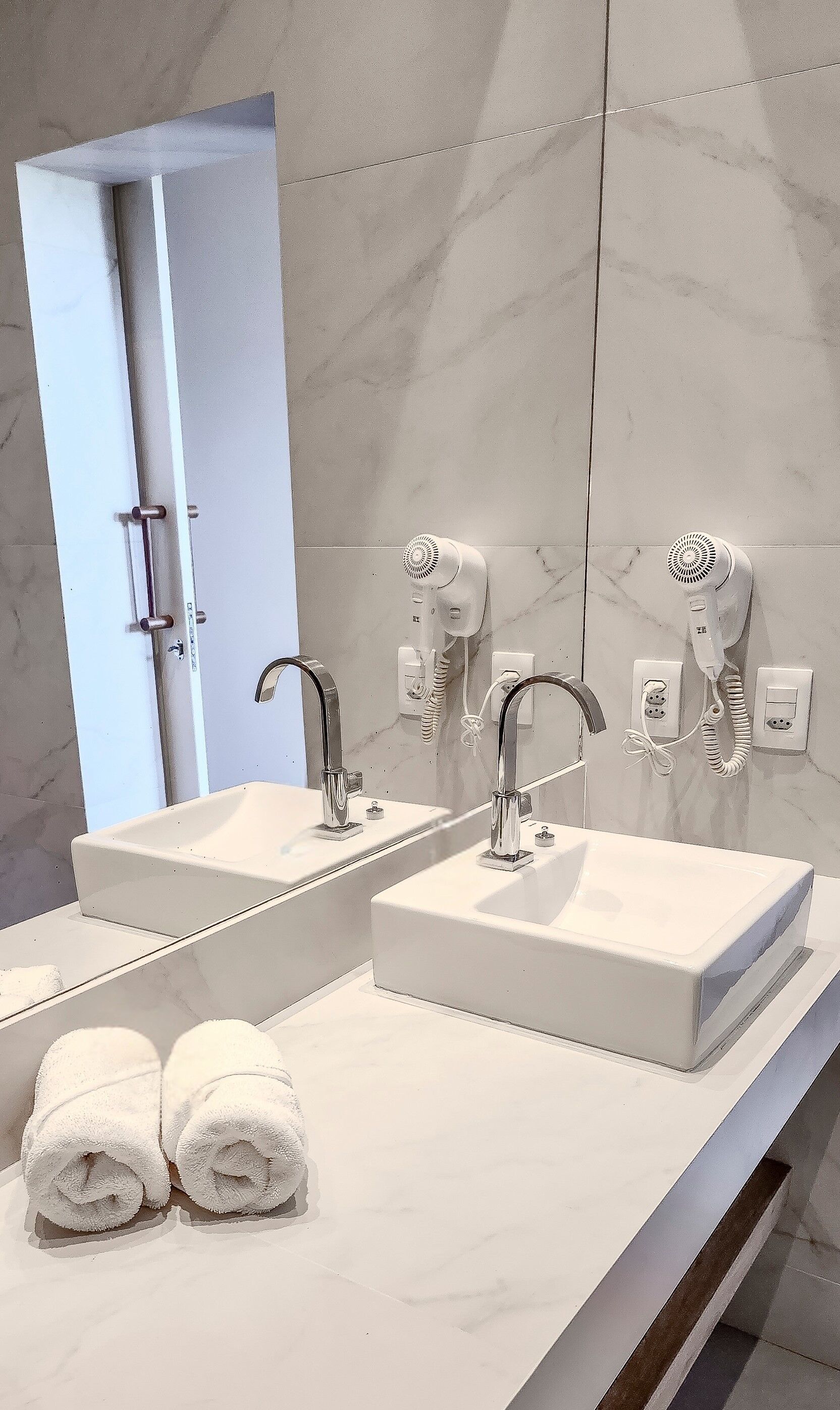 Ein Badezimmer mit zwei Waschbecken, einem Spiegel und einem Fön.