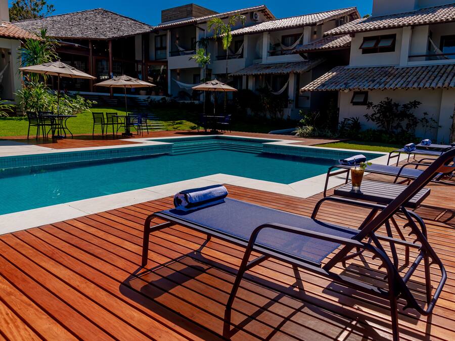 A pool area with wooden deck, lounge chairs, and umbrellas.