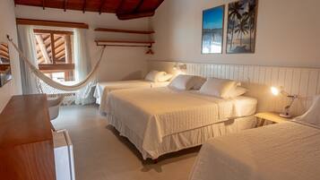 A room with two beds, a hammock, wooden beams, and a view of the beach.