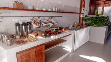 A buffet setup with various food items, including pastries, fruits, and condiments.
