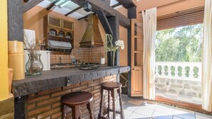 Cozinha com backsplash de tijolos, vigas de madeira e janela com vista para o verde.