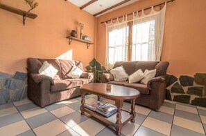 A living room with two brown sofas, a wooden coffee table, and a tiled floor.
