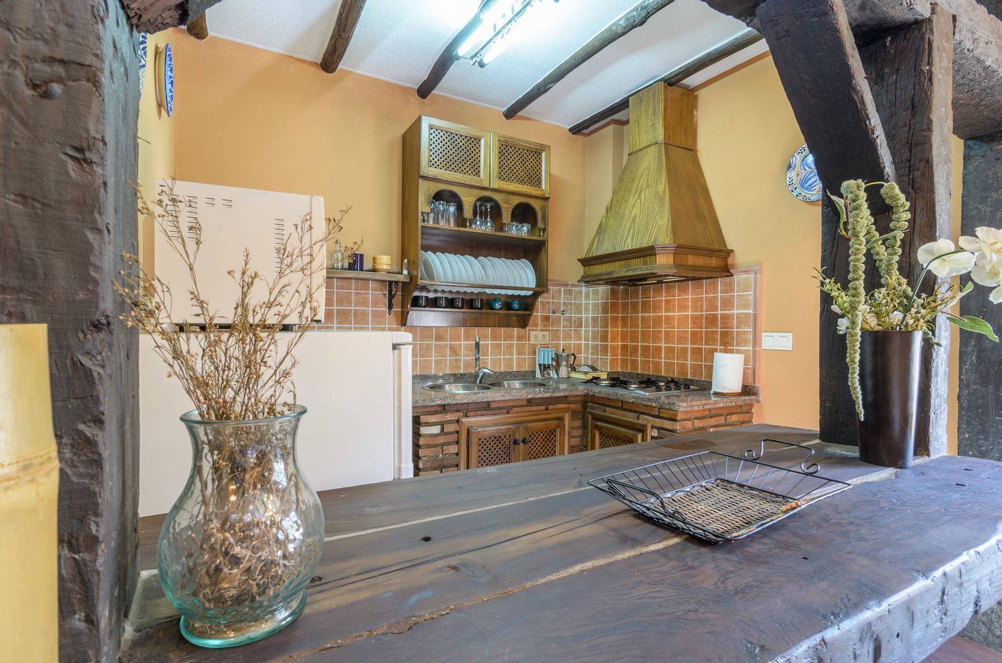 A rustic kitchen with a wooden countertop, a sink, and a hanging pot rack.