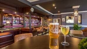 A bar area with a round table, a beer glass, and a wine glass.