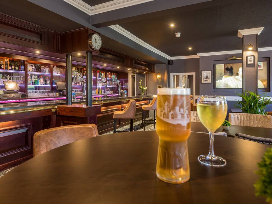 Een bar met een ronde tafel, een biertje en een wijnglas.