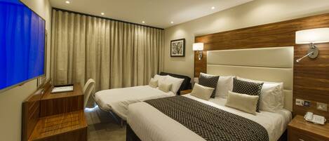 Habitación de hotel con dos camas, un escritorio, una silla, un televisor y un baño.