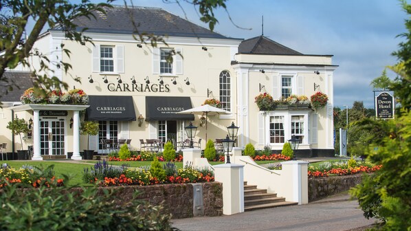 A building with a sign reading "Carriages Bar and Brasserie" and another sign for "The Devon Hotel".