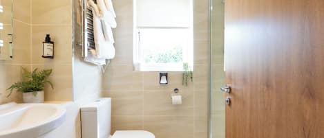Une salle de bain avec des toilettes, un lavabo, une douche et une fenêtre.