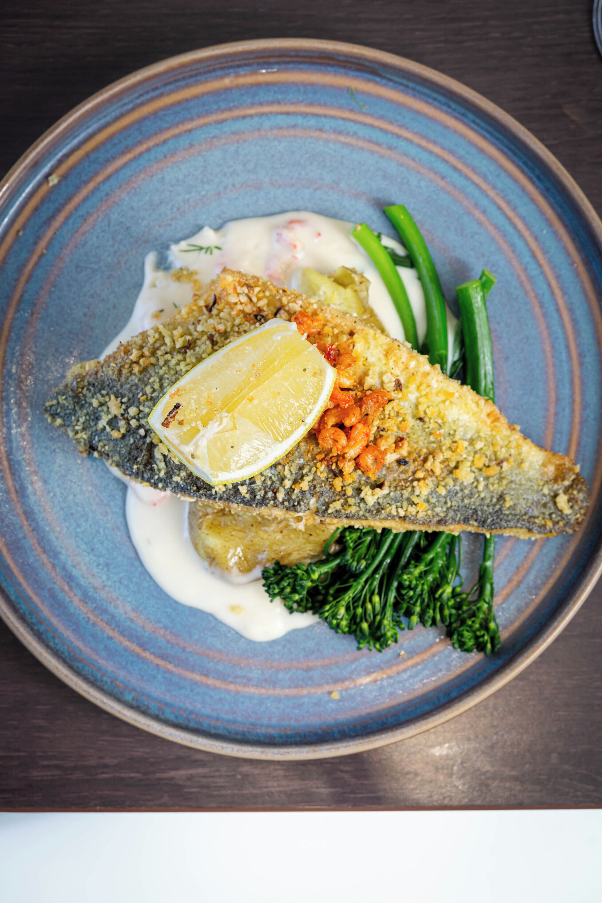 Un plato con pescado, limón y verduras.