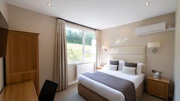 Una habitación de hotel moderna con una cama grande, mesitas de noche, un escritorio y un armario.