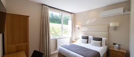 Una habitación de hotel moderna con una cama grande, mesitas de noche, un escritorio y un armario.