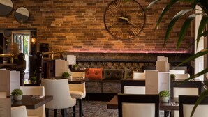 A restaurant with brick walls, round tables, and cushioned seating.
