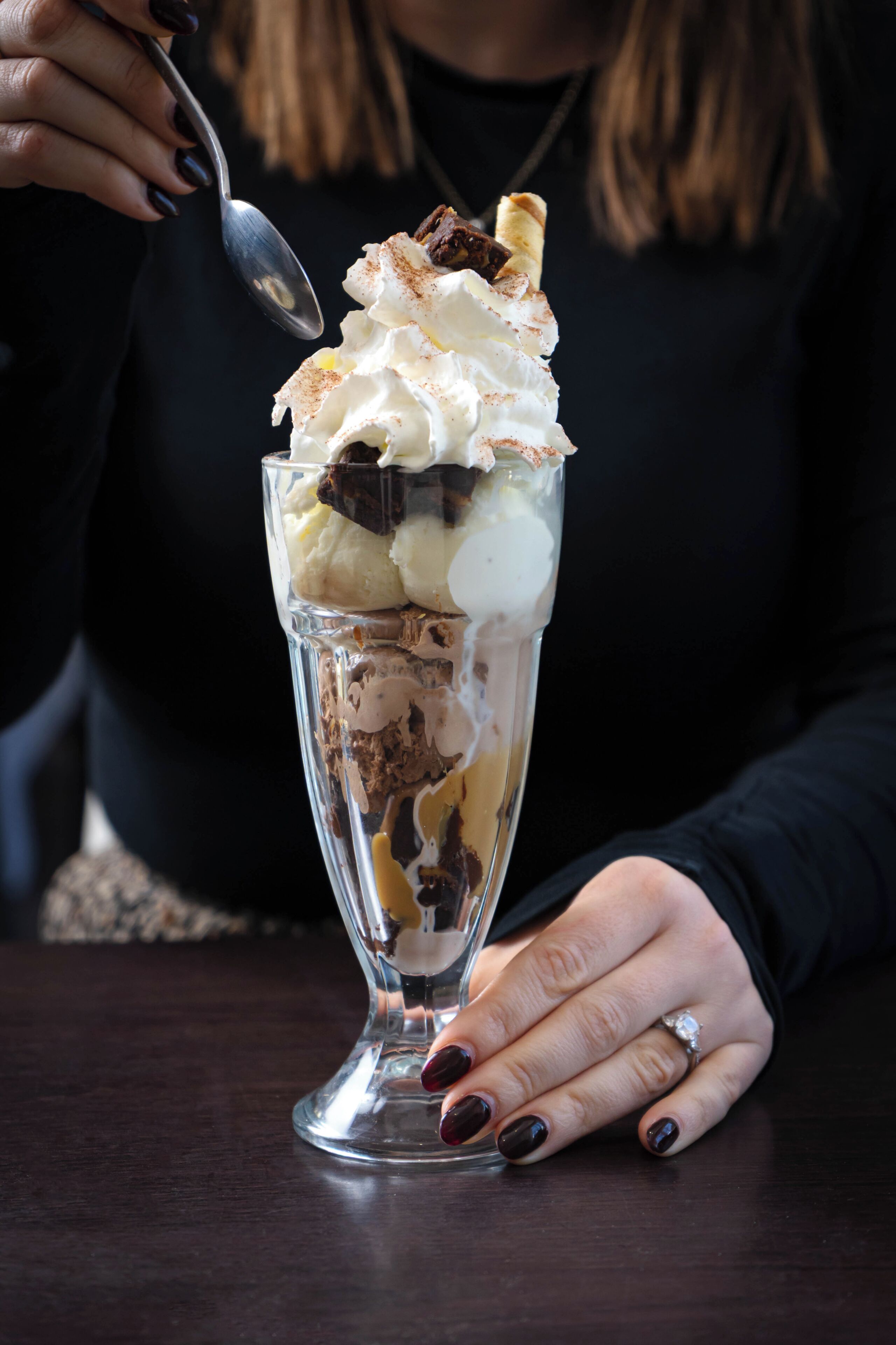A dessert in a clear glass cup with whipped cream and chocolate pieces.