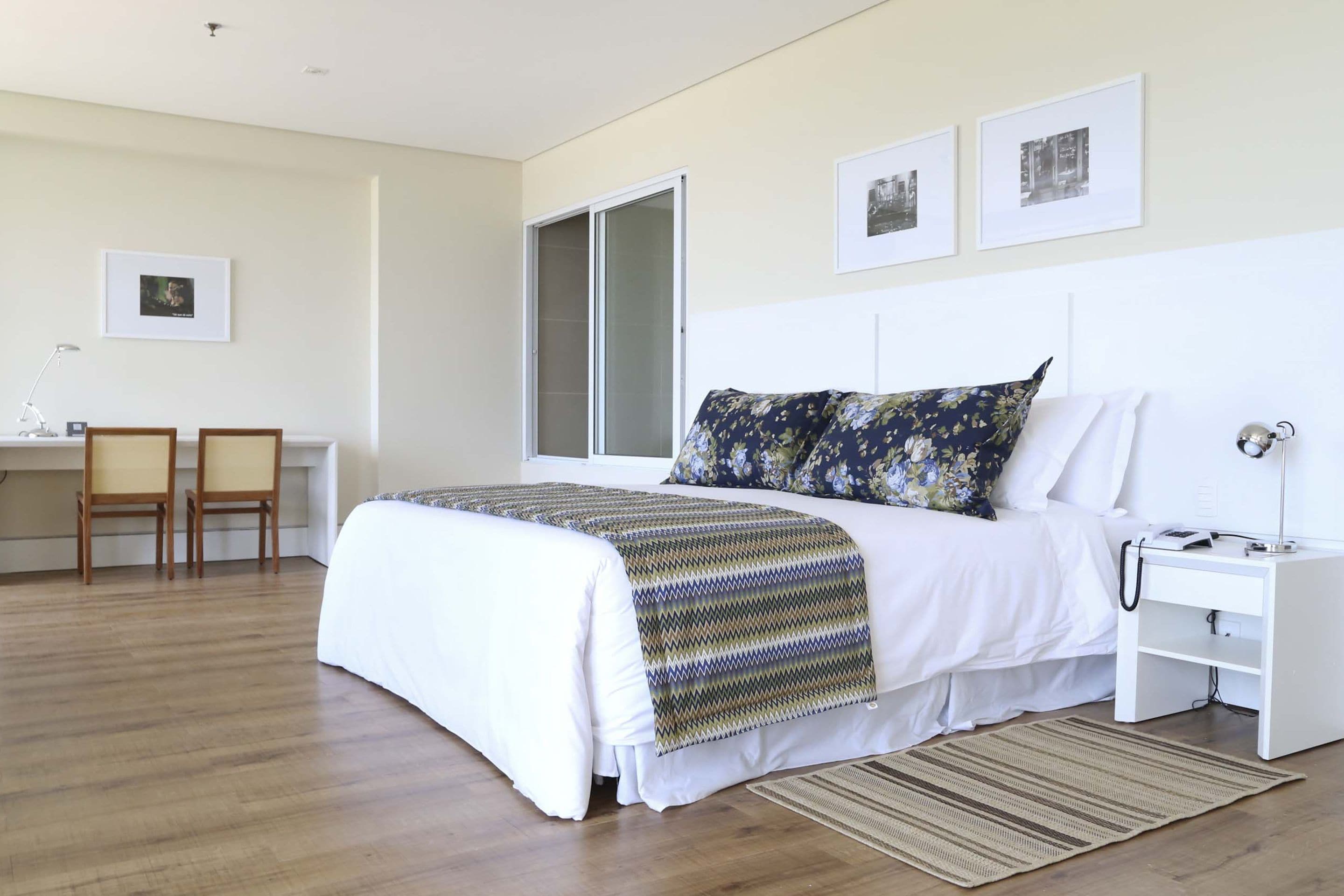 A neatly arranged bedroom with a bed, bedside table, lamp, and two chairs.