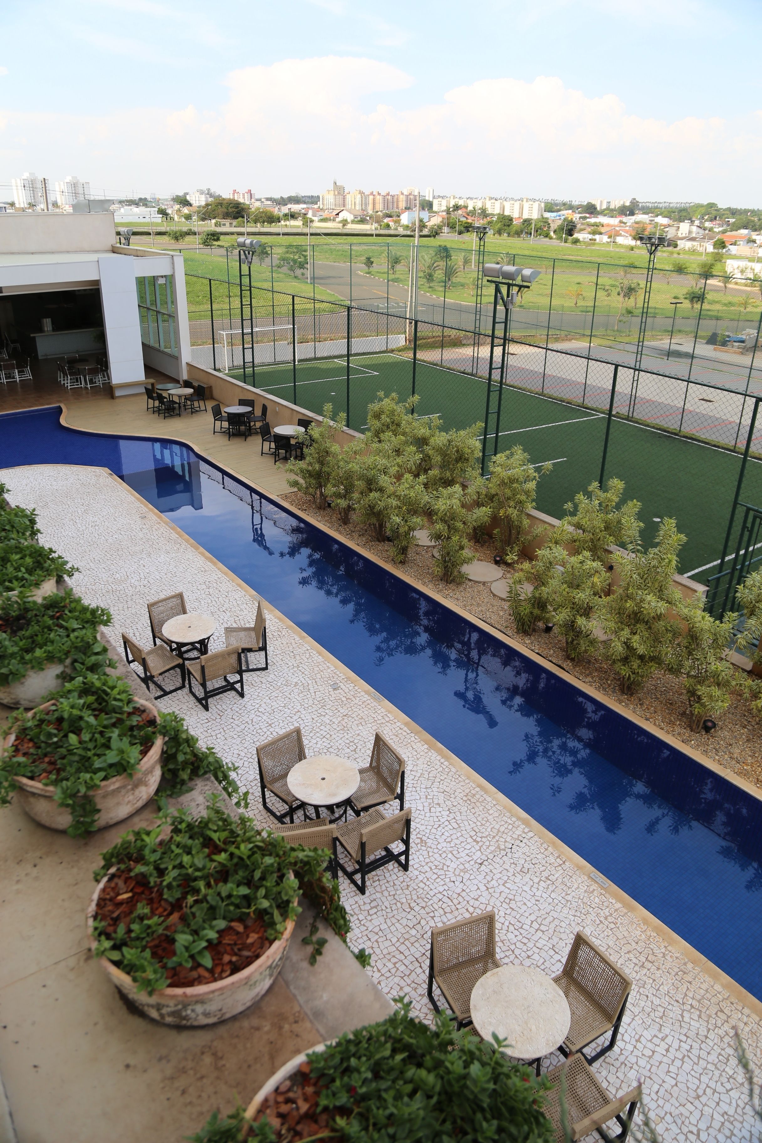 A rooftop pool area with outdoor seating and a view of a sports field.