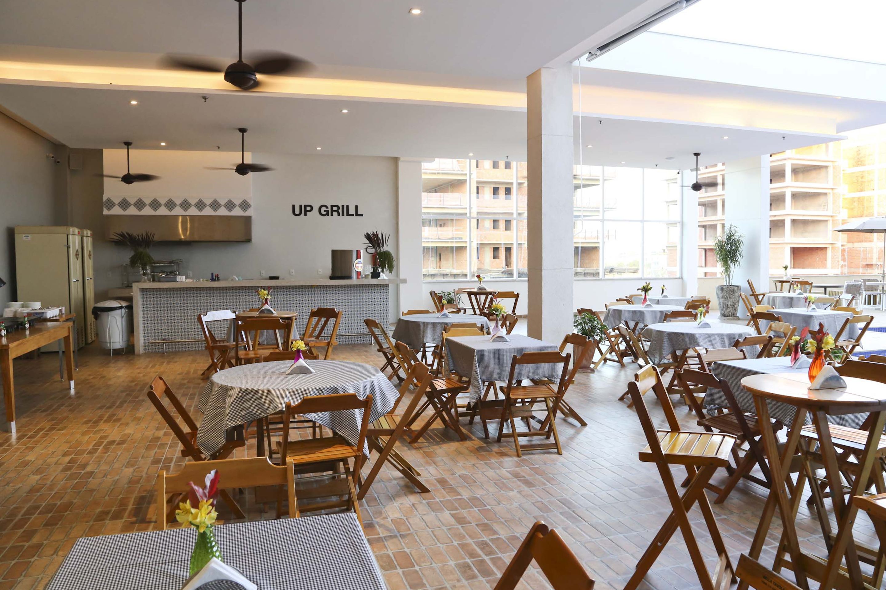 A restaurant with multiple tables and chairs, a kitchen area, and a sign reading "UP GRILL".