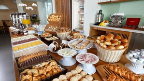 A buffet with various food items including pastries, breads, and cheeses. - Vitória Hotel Convention Paulínia (Paulinia)