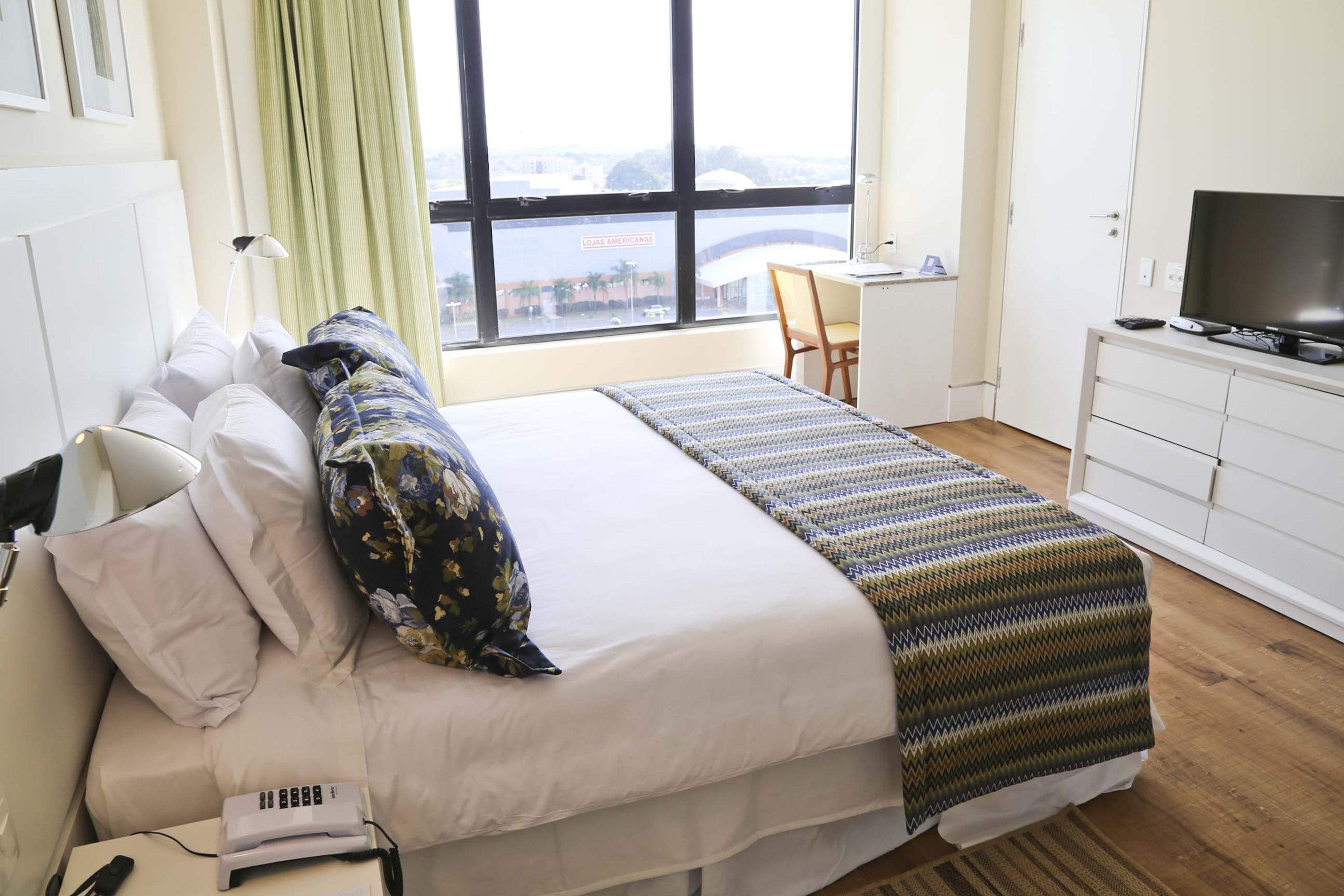 Habitación de hotel con cama, escritorio, televisor y vista a un puente.