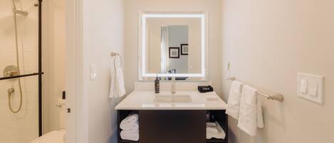 A modern bathroom with a toilet, shower, and sink.