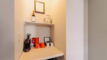 A kitchenette with a coffee maker, mugs, a wine bottle, and a framed certificate on the wall.