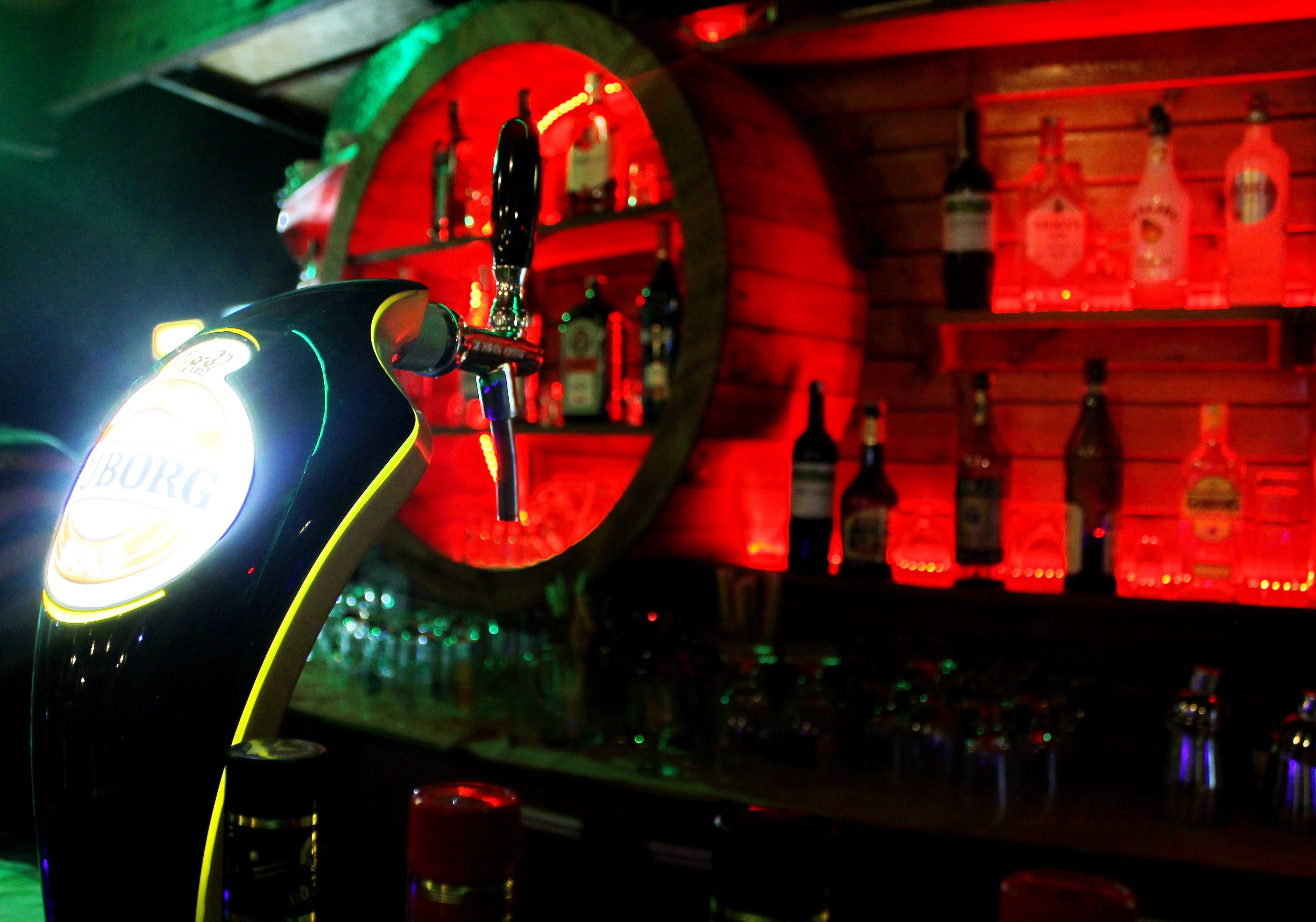 Un espace bar avec un robinet à bière et des étagères remplies de bouteilles d’alcool.