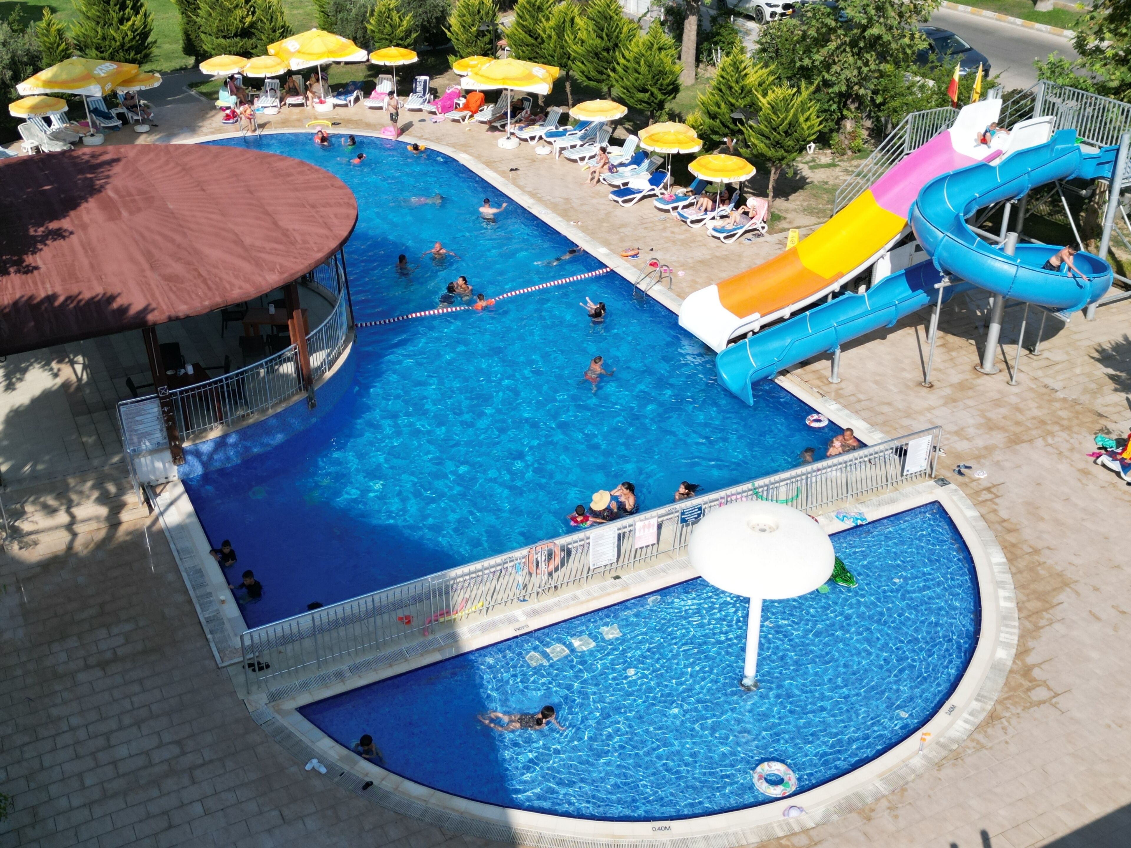 Une grande piscine extérieure dotée de plusieurs toboggans et de transats.