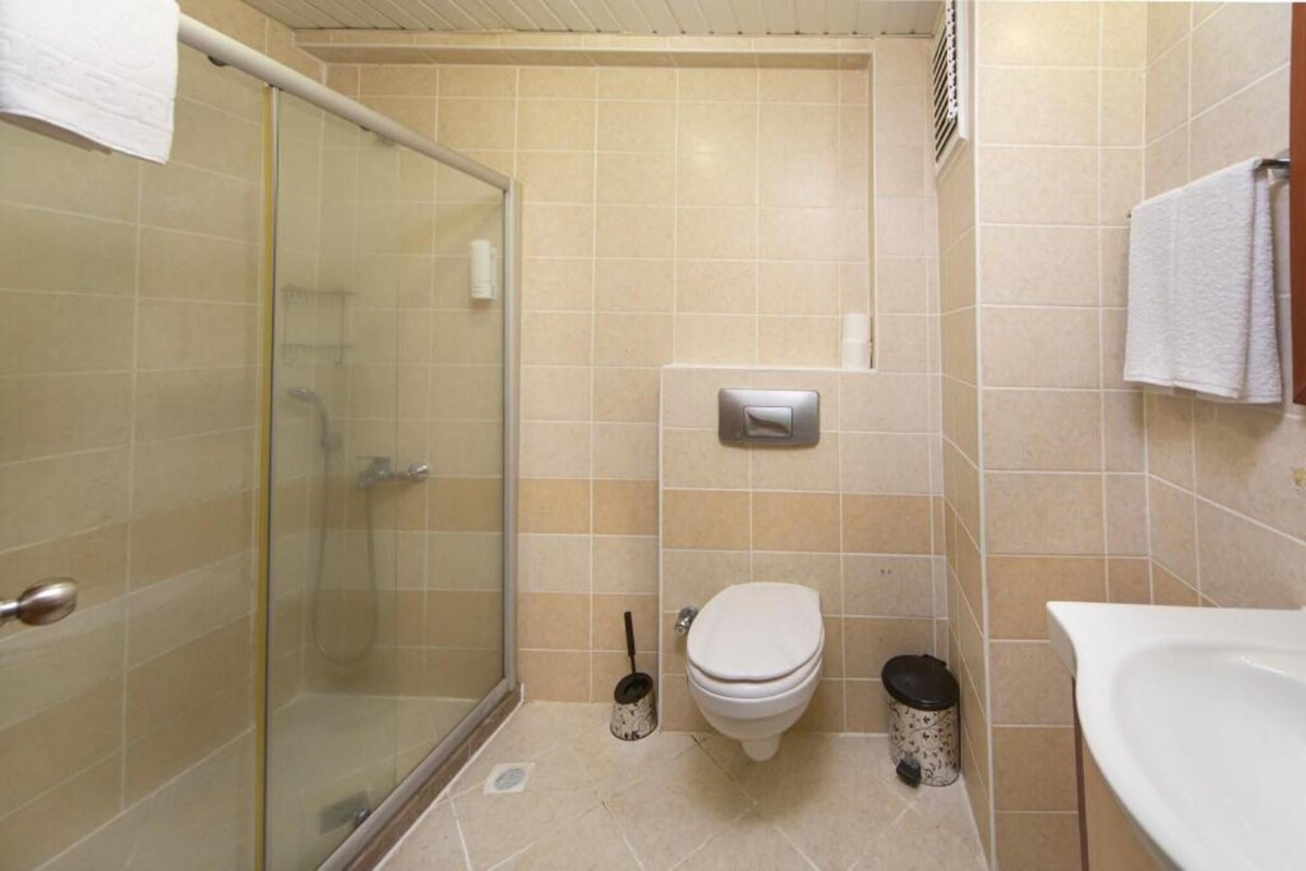 A bathroom with a glass shower enclosure, a toilet, a bidet, and a sink.