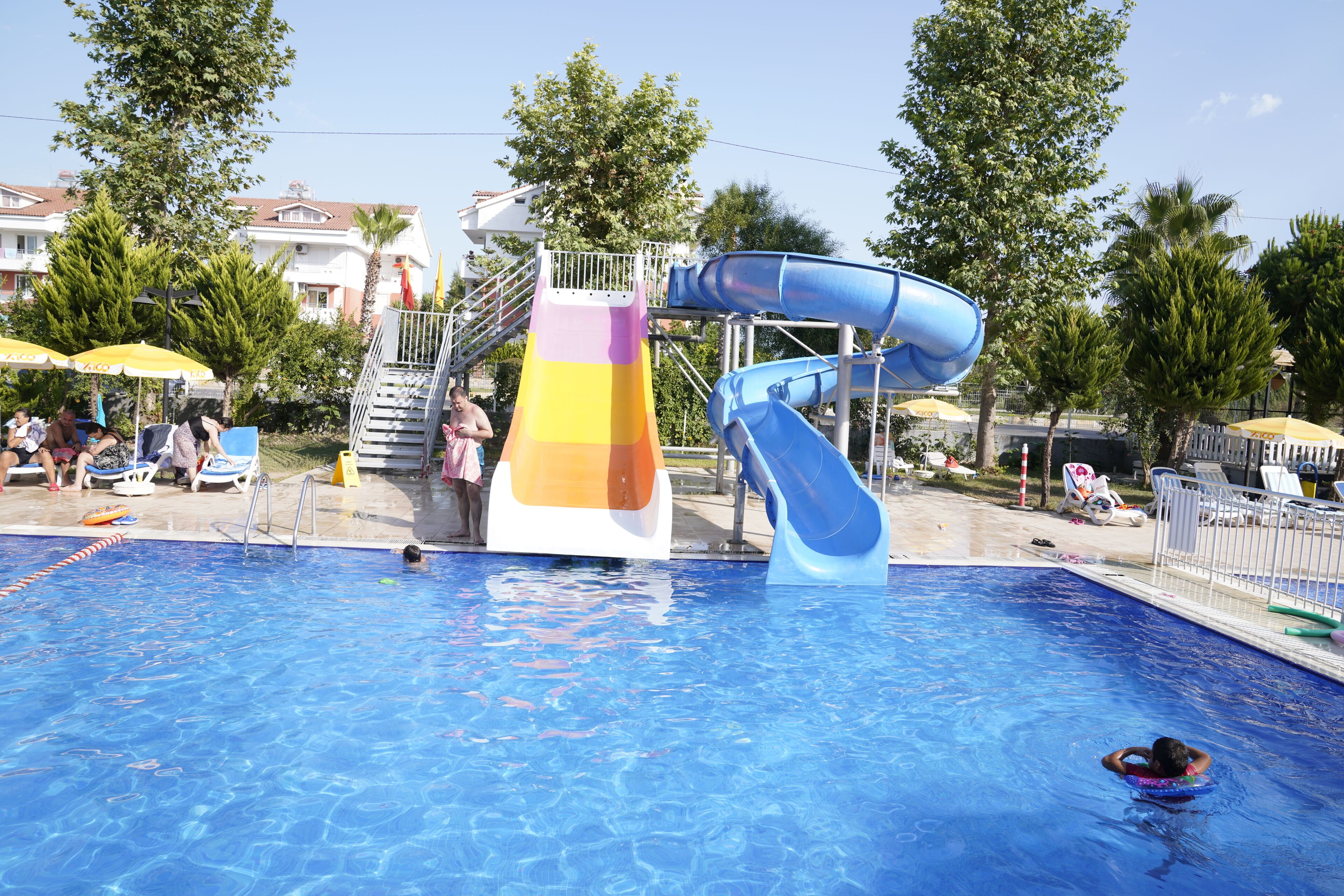 A swimming pool with a water slide and a multi-colored slide tower.