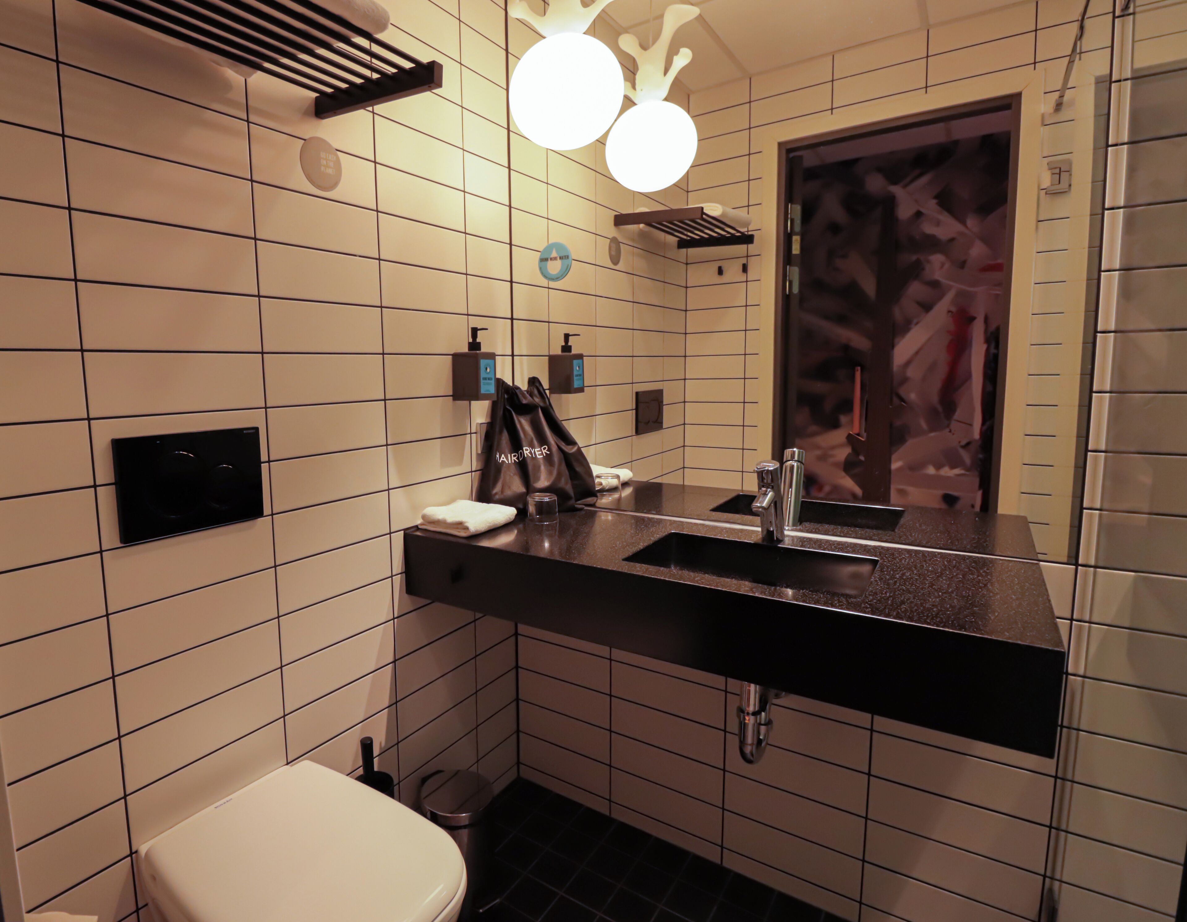 A modern bathroom with a black countertop, a white toilet, and a mirror with a decorative frame.