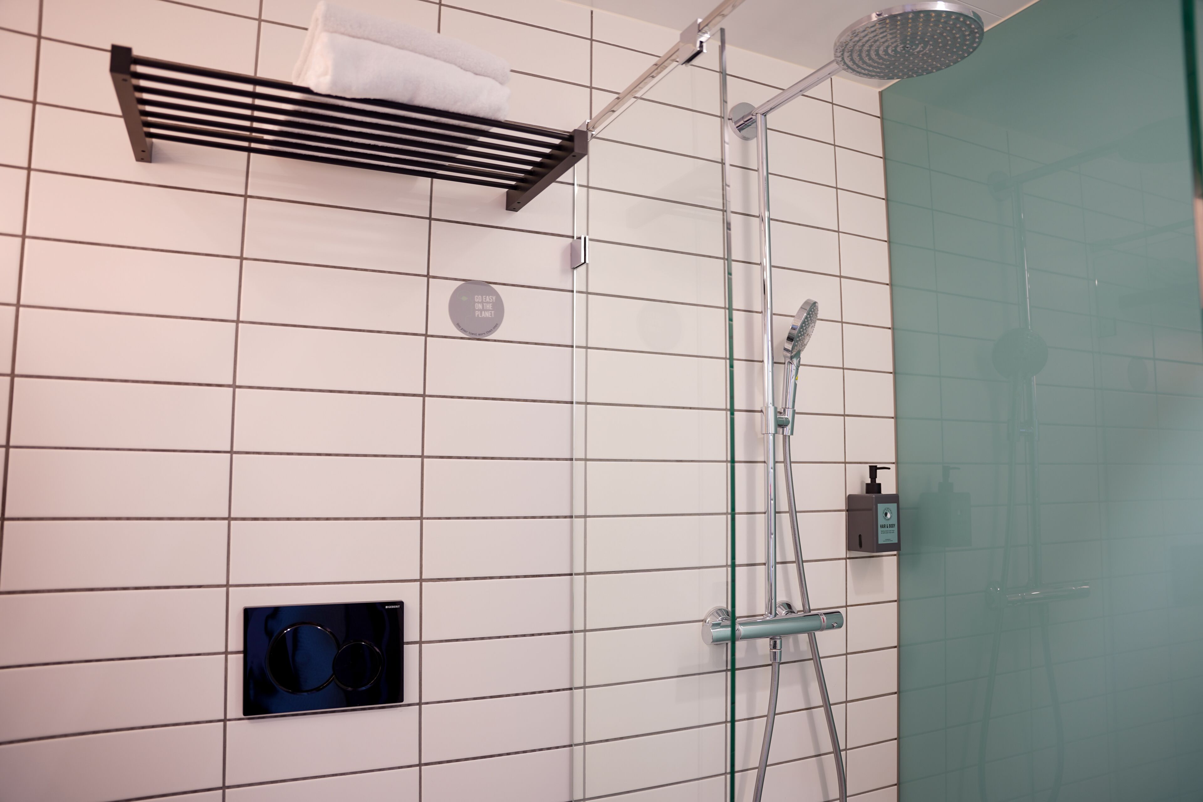 Um banheiro moderno com box de vidro, porta-toalhas e dispenser de sabonete.