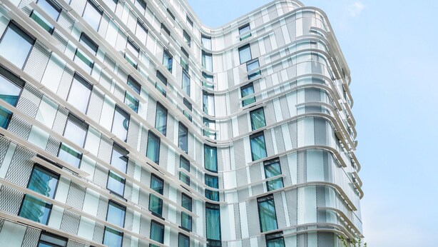 A modern building with a curved facade, large windows, and a clear sky. - Ibis Styles Paris Charles de Gaulle Airport (Tremblay-en-France)
