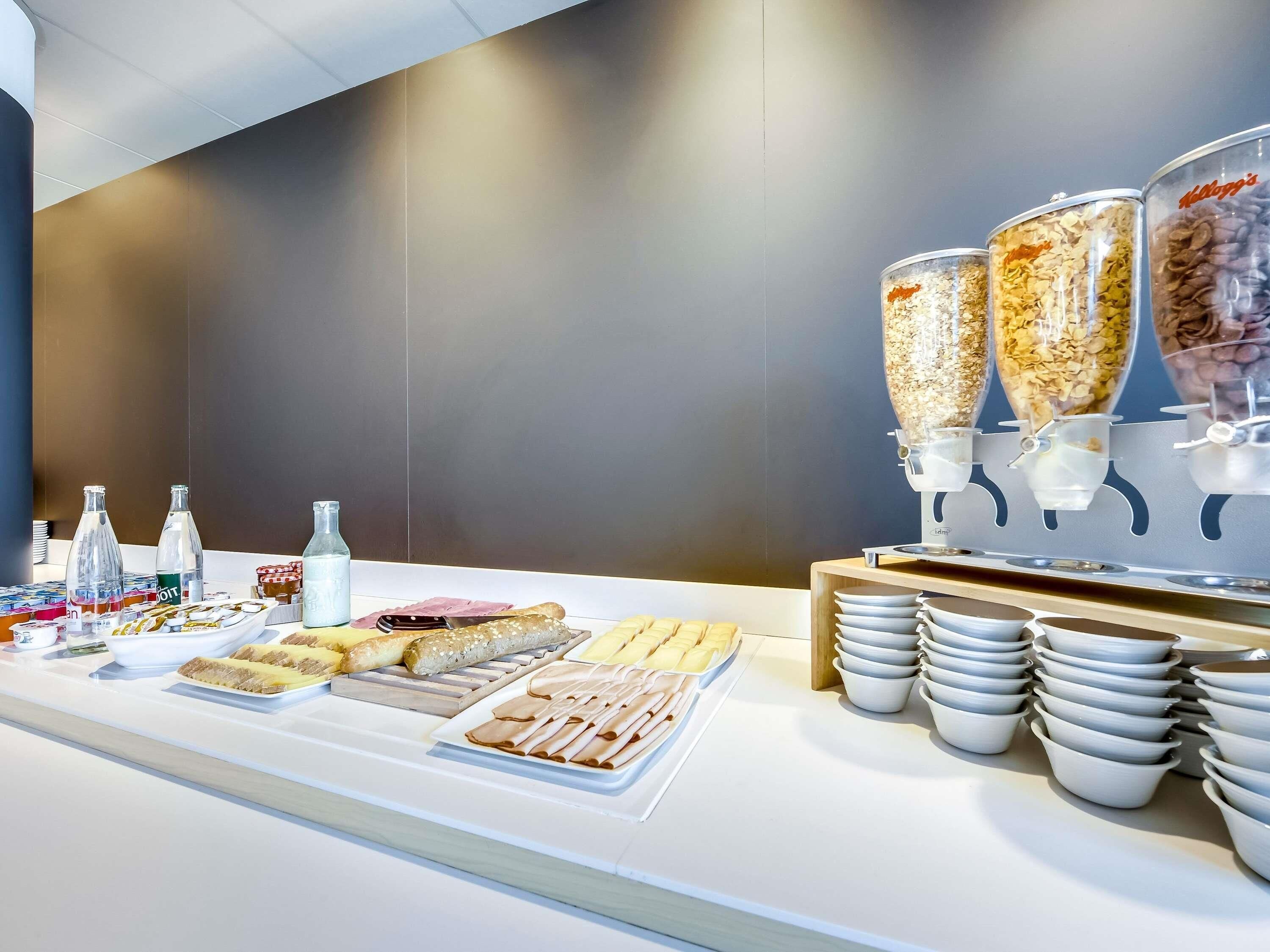 Un bufé con diversos alimentos y bebidas, como cereales, pasteles y leche.