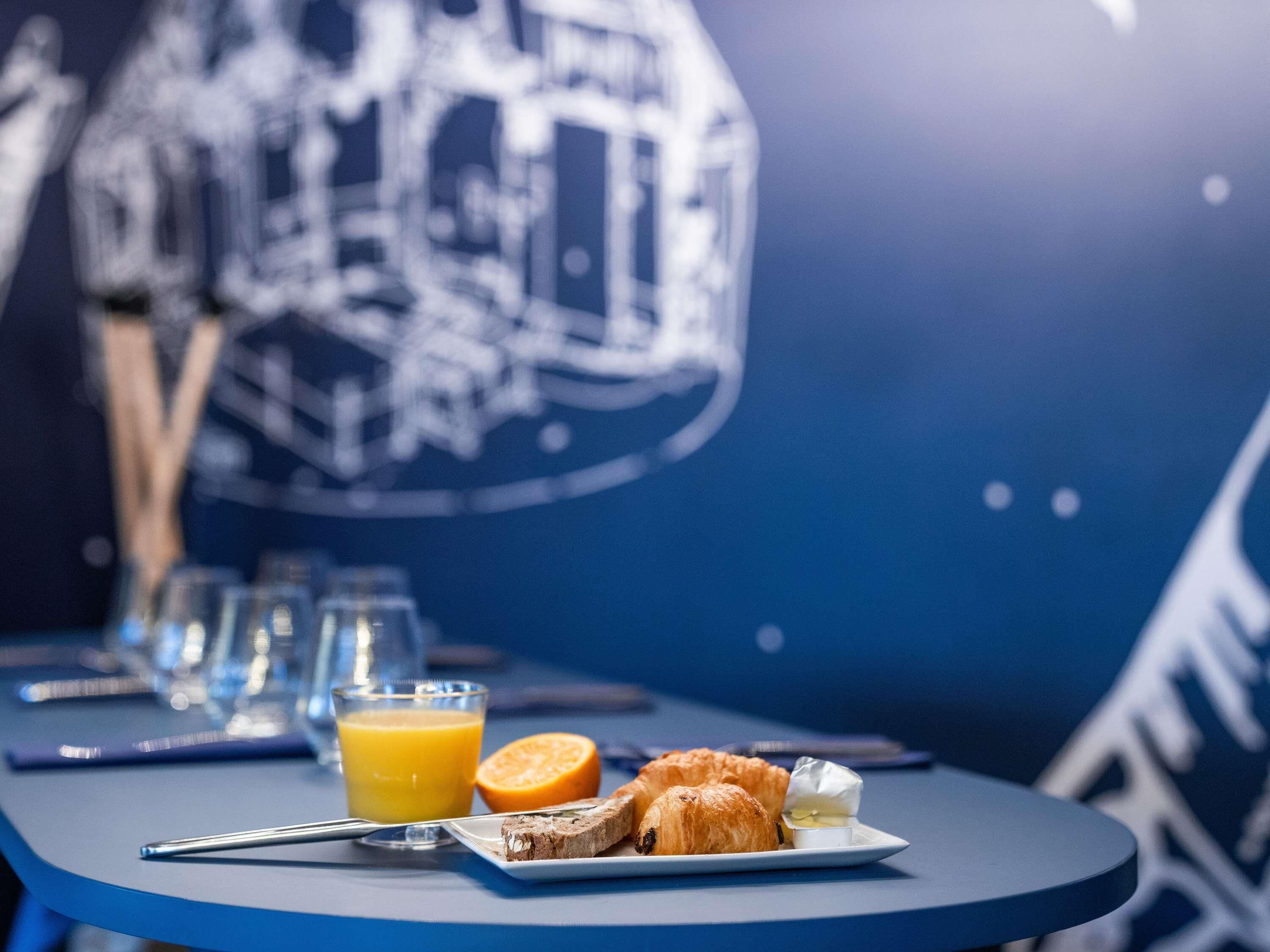 Een ontbijttafel met croissants, sinaasappelsap en een klein bakje boter.