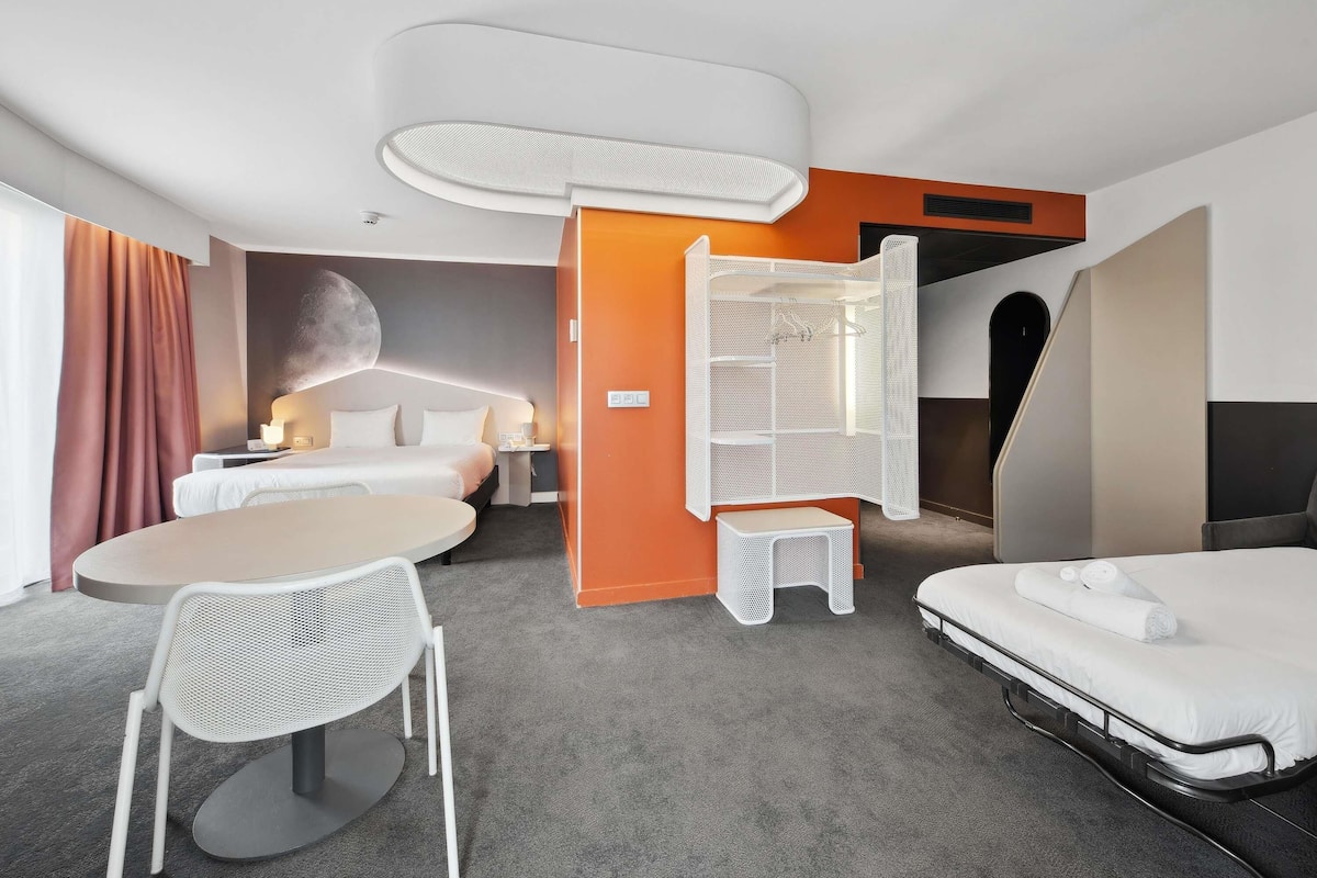 Une chambre d’hôtel avec un lit, un bureau, une chaise et une petite table.