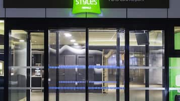 The entrance to ibis Styles Paris CDG Airport hotel with a glass door and a green sign.
