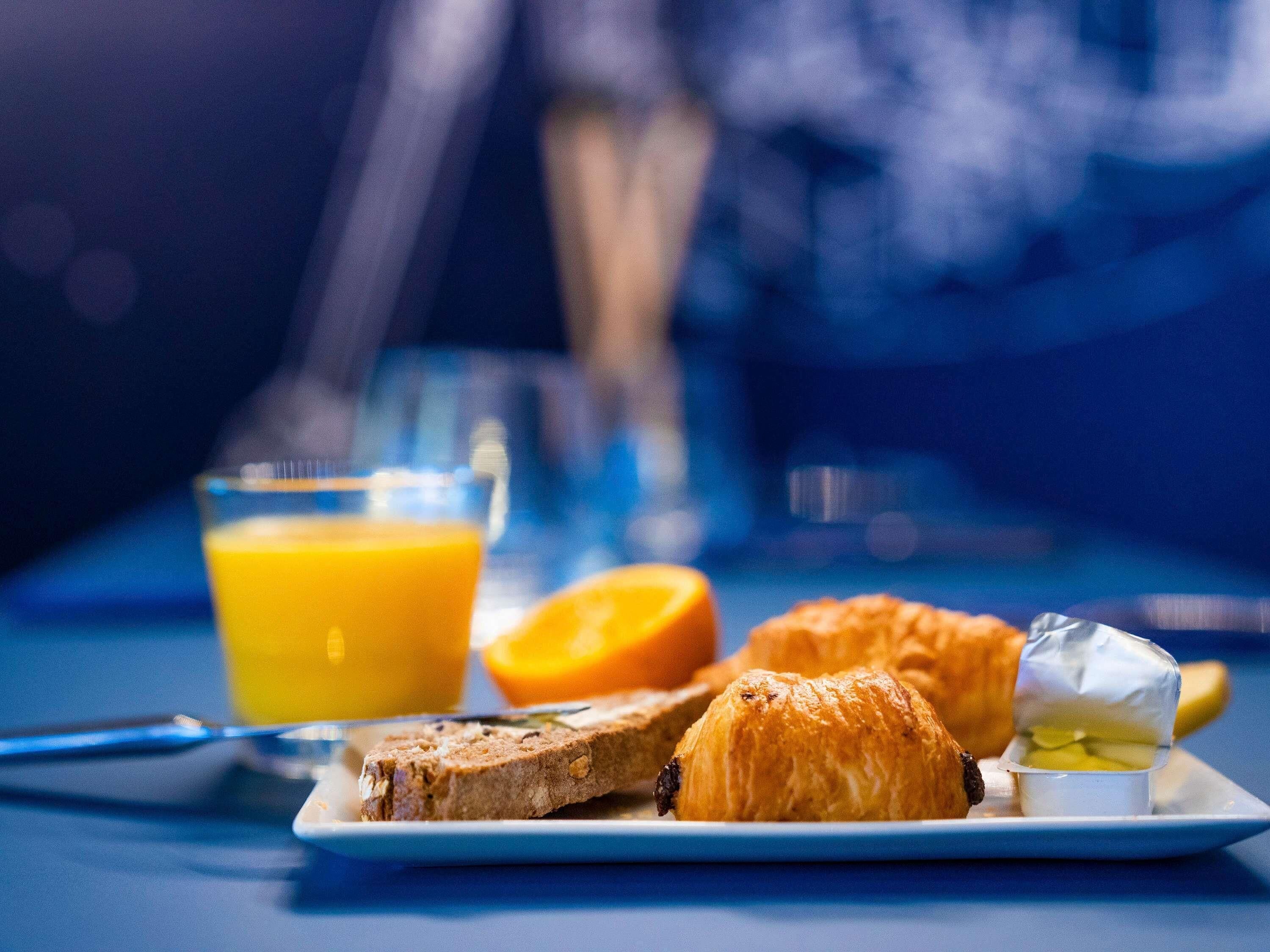 A breakfast plate with toast, a croissant, and a glass of orange juice.