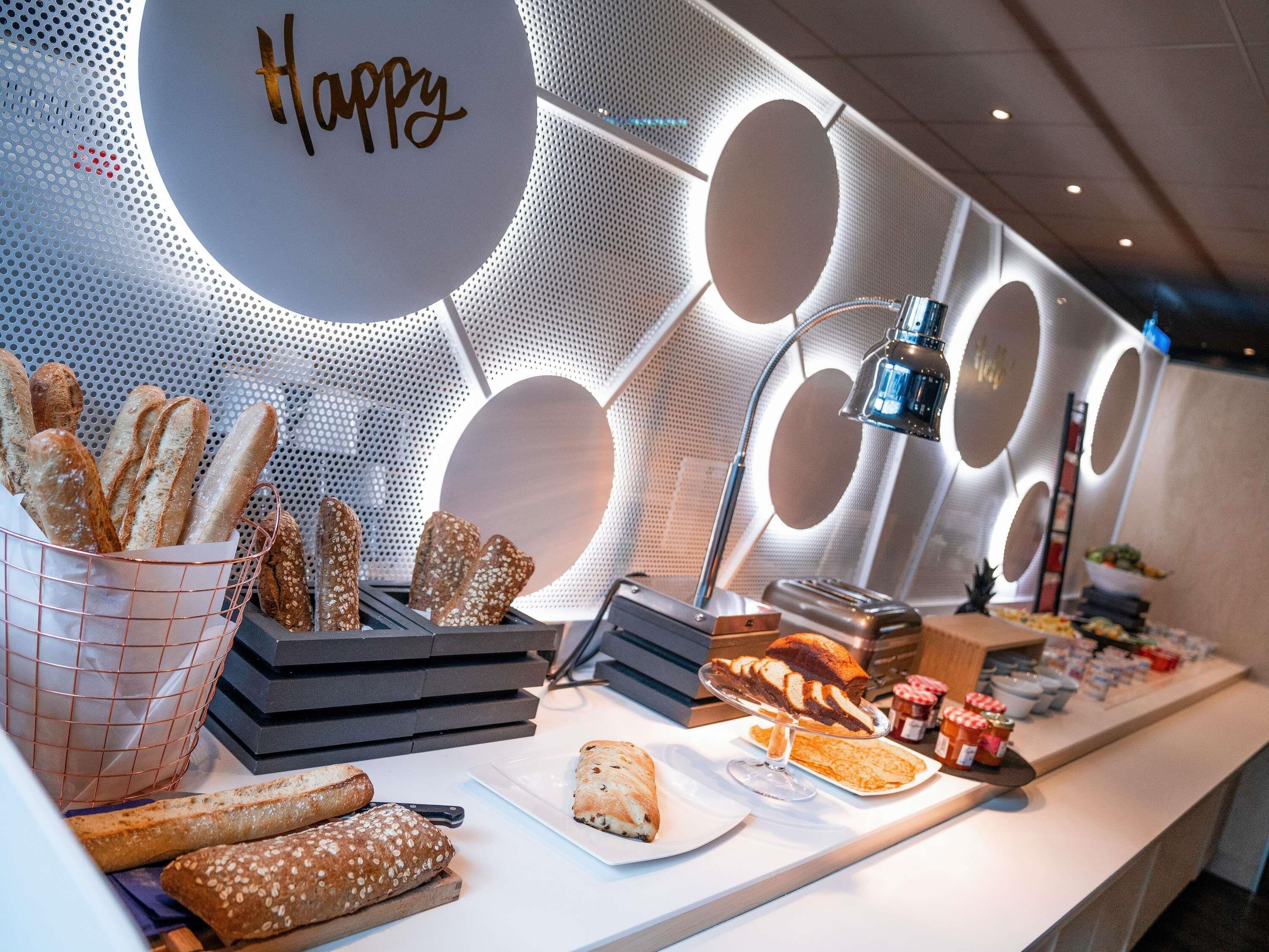 A buffet with various breads and pastries, a 'Happy' sign, and a modern interior design.
