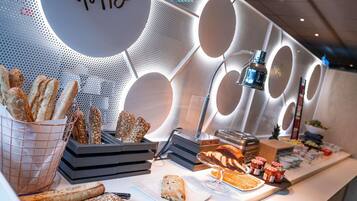 A buffet with various breads and pastries, a 'Happy' sign, and a modern interior design.