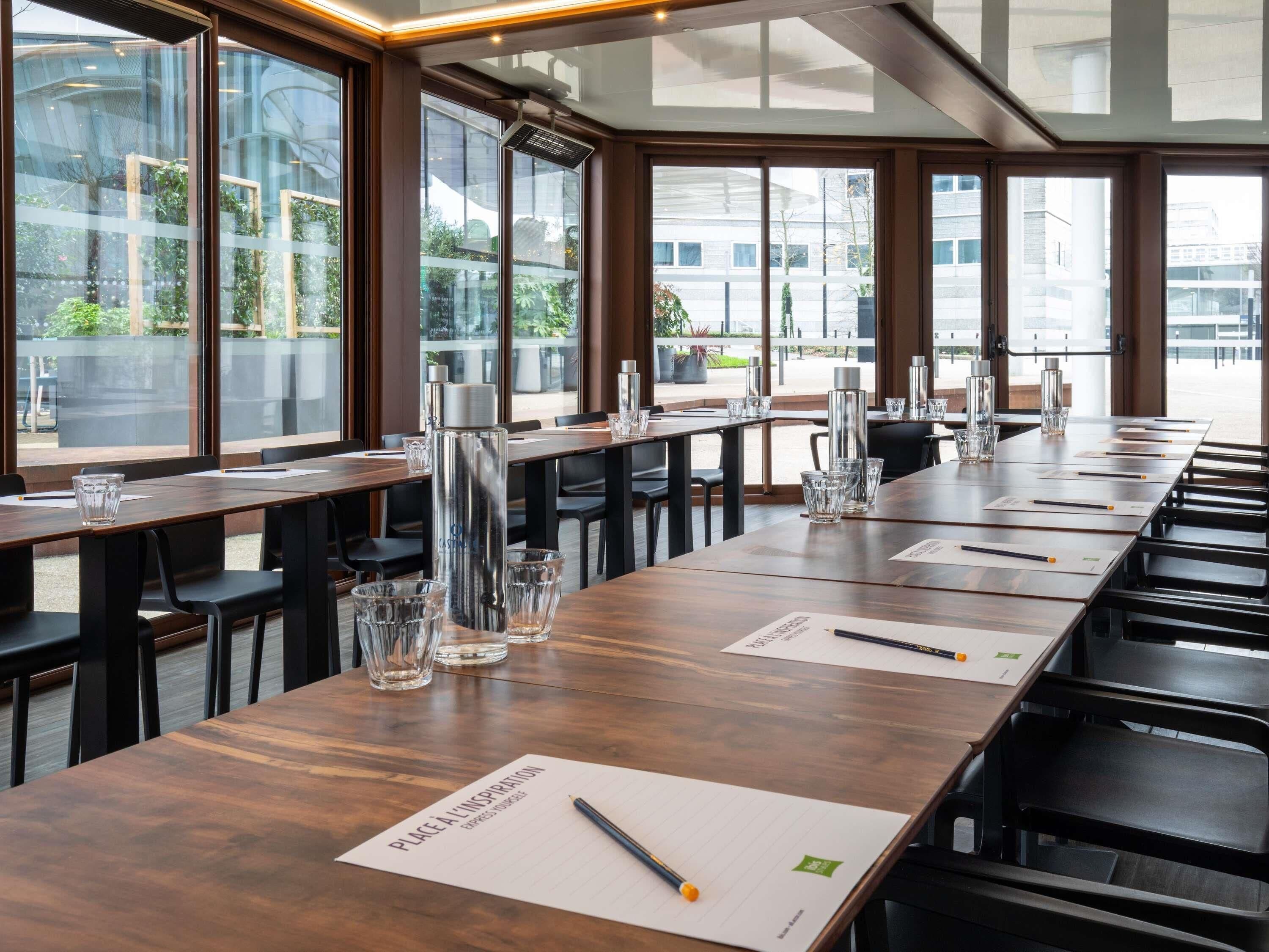A conference room with long tables, chairs, and glass water bottles.