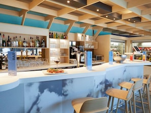 Un espace bar avec un comptoir, des tabourets et des étagÚres remplies de bouteilles et de verres.