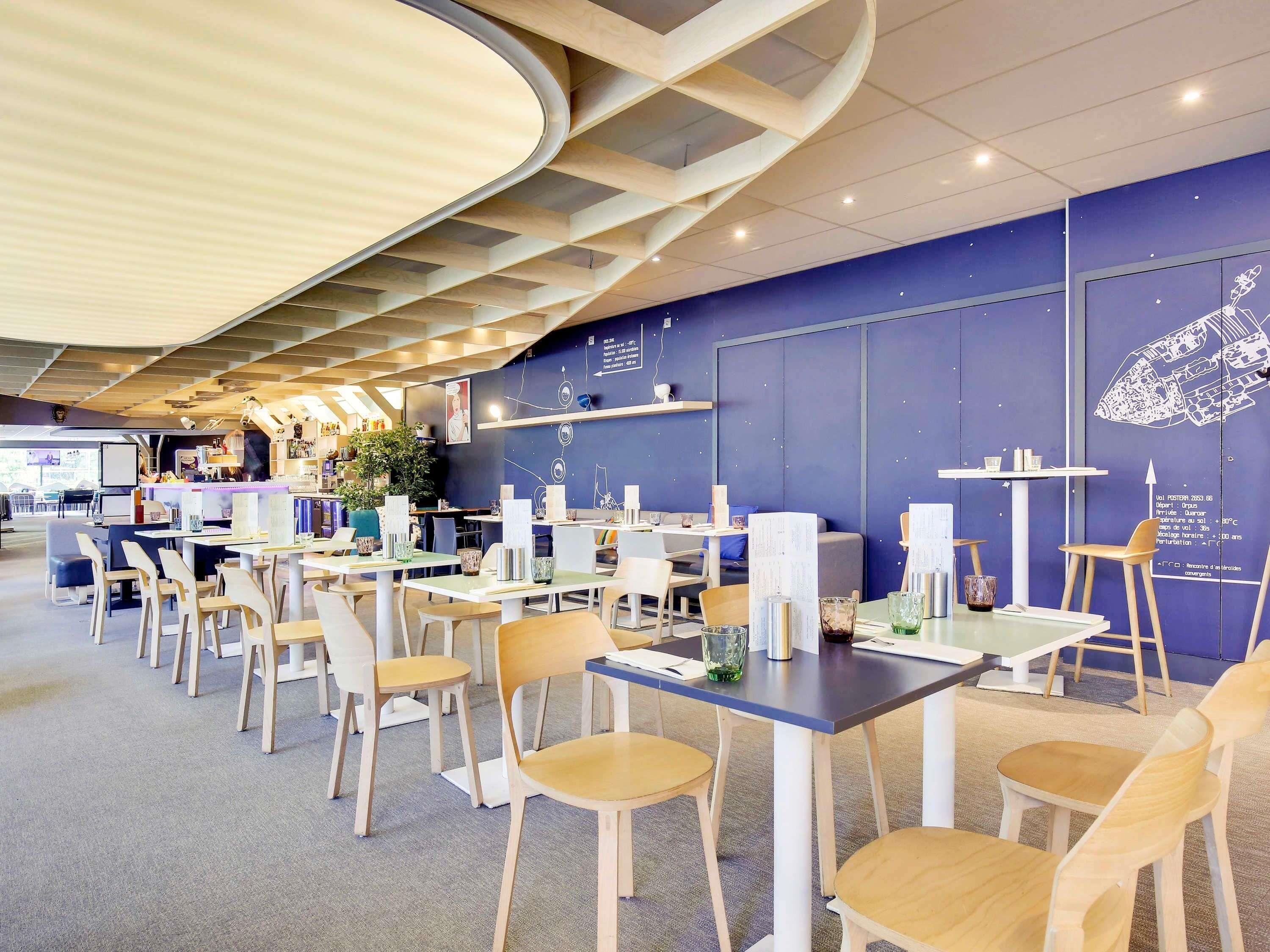 A modern dining area with tables and chairs, a bar area, and a wall with a decorative element.