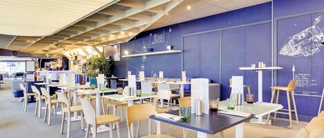 A modern dining area with tables and chairs, a bar area, and a wall with a decorative element.