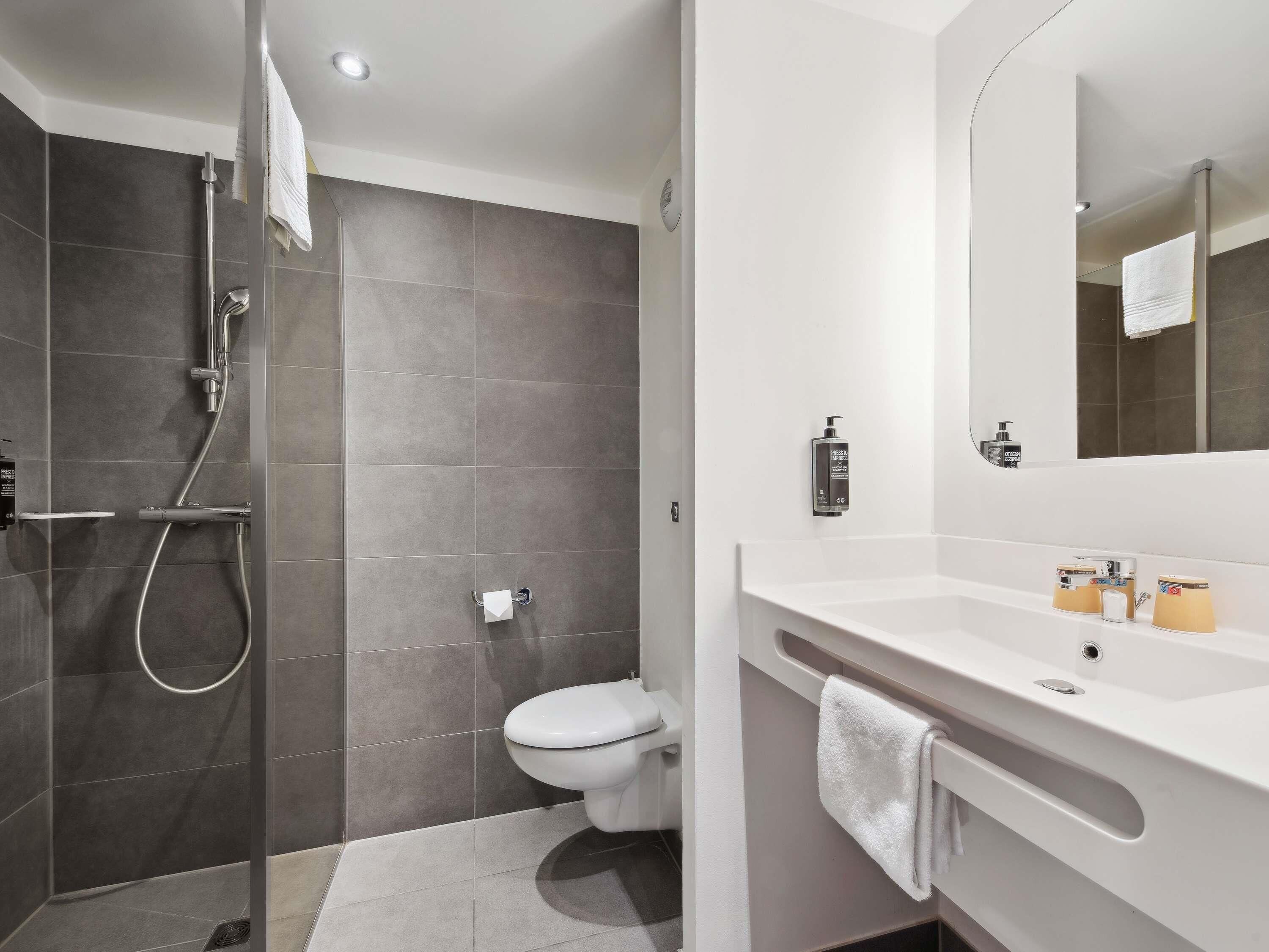Un baño moderno con ducha, inodoro y lavamanos con espejo.