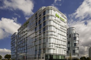 Un hotel moderno con fachada curva, varios balcones y ventanas amplias.